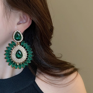 Close-up of model wearing luxury emerald teardrop floral earrings with crystal detailing