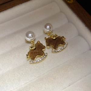 Macro detail of red pony pearl earrings with gold accents in a premium jewelry box