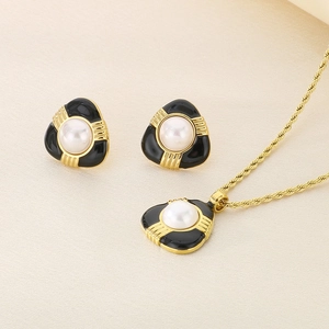 Set vintage francese con collana di perle e orecchini a triangolo su tessuto beige