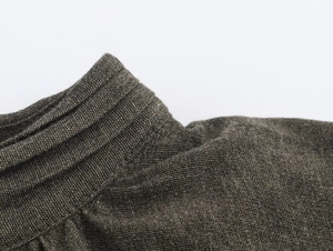 Close-up of olive green knitted fabric showing fine texture and neckline craftsmanship