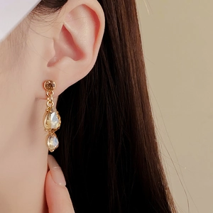 Nahaufnahme eleganter goldener Tropfenohrringe mit champagnerfarbenen Kristallen