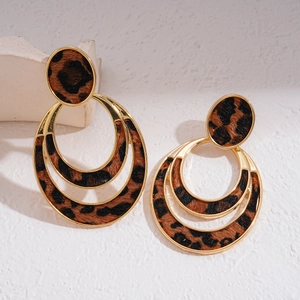 Detail of leopard print pattern on gold geometric double circle earrings on white background