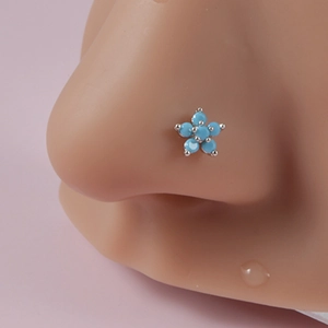 Macro shot of silver flower nose stud with five blue turquoise stones on a model