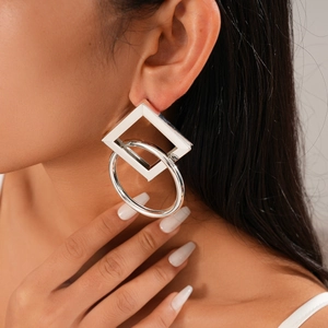Close-up of interlocking square and circle geometric silver earrings on a female model
