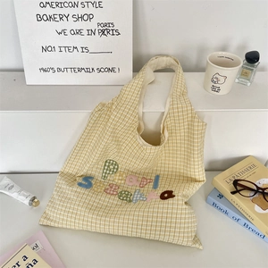 Detail of colorful towel embroidery letters on yellow and white checkered tote bag