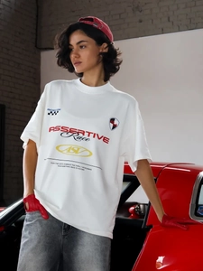 Λεπτομέρεια λευκού oversize t-shirt με τύπωμα αγώνων και φόντο ένα κόκκινο αυτοκίνητο