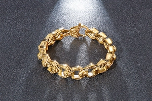 Detailed close-up of gold skull link bracelet with a secure lobster clasp on dark background