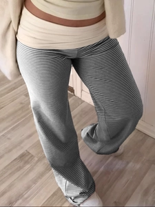 Detail of high waist striped trousers with beige wide folded waistband on wooden floor