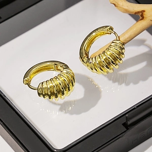 Gros plan de boucles d'oreilles cœur dorées avec perles et design texturé sur support
