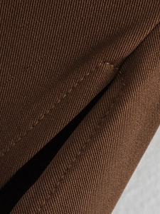 Macro shot of high-quality brown twill fabric texture and fine stitching on shoulder padded top