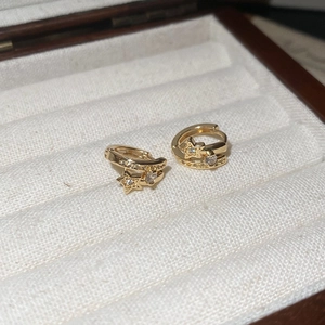 Détail macro de créoles plaquées or 18 carats avec étoiles et cristaux dans un écrin à bijoux