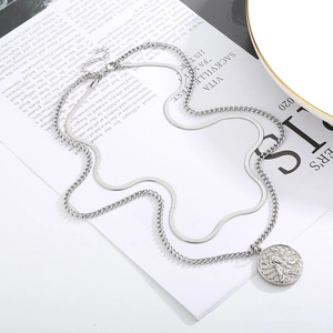 Detail of silver double-layered chain necklace featuring a vintage religious medal pendant