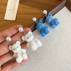 Detail of cute flocked bear earrings with pearls in blue and white colors