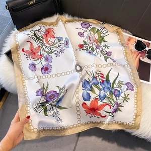 Dettaglio foulard di seta con stampa floreale e bordo a catena dorata su pelliccia