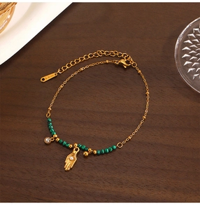Détail du bracelet en acier inoxydable doré avec perles de malachite et breloque œil de palm