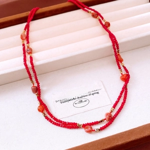 Detail of red beaded necklace with golden accents in a beige velvet jewelry box