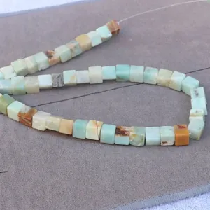 Close-up of square natural stone beads with colorful textures and cube cut for jewelry DIY