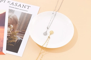 Flat lay of gold and silver layered necklaces with coin pendants on a ceramic plate