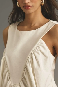 Close-up of sleeveless beige top with elegant pleated neckline and textured fabric
