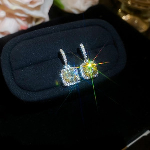 Macro shot of yellow square gemstone earrings with sparkling halo in a black velvet jewelry box