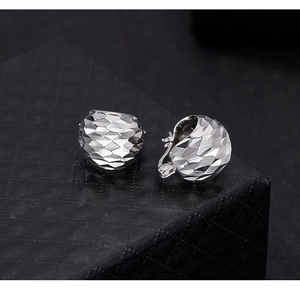 Macro shot of silver CNC laser cut hoop earrings with shimmering geometric patterns