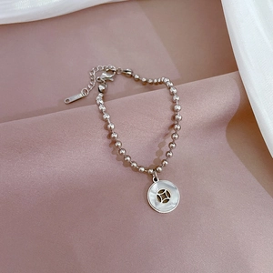 Silver stainless steel beaded bracelet with white shell coin pendant on soft fabric