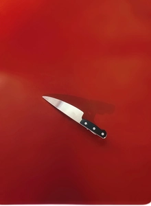 Detail shot of mini dagger hair clip with silver blade and black handle on red background