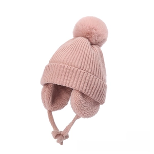 Detail of pink knitted baby hat featuring soft fleece lining and fluffy pom-pom decoration
