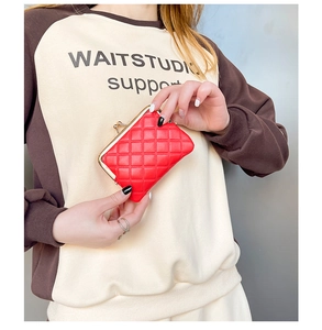 Detailed view of a mini red quilted coin purse held by a hand to show compact size