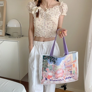 Détail du cabas en toile avec imprimés de dessins animés et poignées violettes