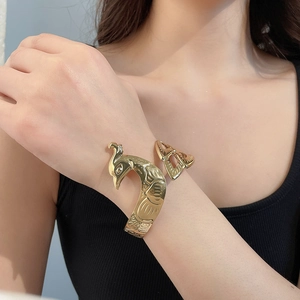 Detaillierte Nahaufnahme eines eleganten goldenen Armreifs in Pfauenform am Handgelenk