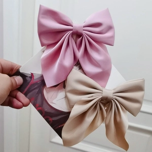 Macro shot of pink and beige satin bow hair clips showing smooth fabric texture