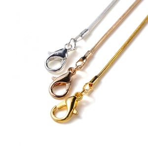Detailed macro view of snake chain necklaces with lobster clasps in gold silver and rose gold