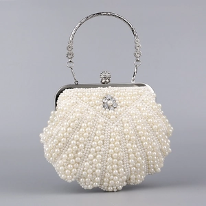 Detail shot of the elegant shell-shaped pearl clutch bag with carved silver handle