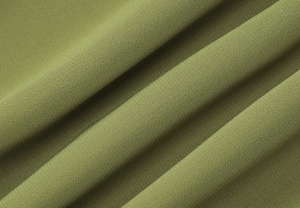 Détail macro de la texture du tissu en mousseline verte avec des plis diagonaux sur la robe