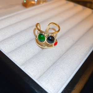 Close-up of a gold-plated dragon ring featuring green, black, and red circular stones