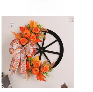 Macro detail of autumn wreath featuring pumpkins, orange roses, and a plaid bow on a wheel