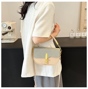 Detail of a chic patchwork saddle bag with gold metal clasp and dual shoulder straps