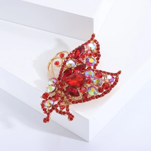 Luxurious gold butterfly brooch with red gemstones and rainbow crystals on a white pedestal