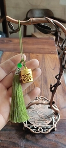 Detail van gouden diffuser hanger met groene kraal en olijfgroene zijden kwastje