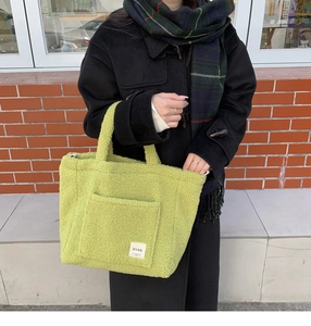 Detail of light green faux shearling tote bag with a soft plush texture and side pocket