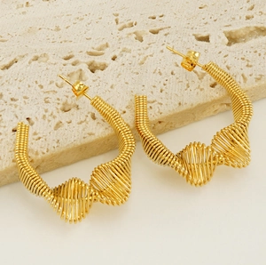 Macro detail of gold spring coiled hoop earrings on a textured stone display