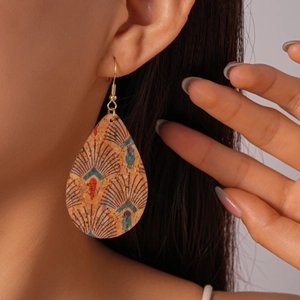 Macro shot of bohemian teardrop cork earring with colorful ethnic feather pattern on model