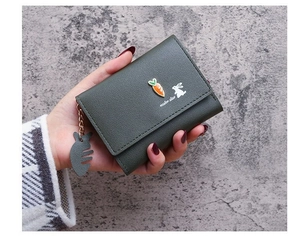 Detail of dark green tri-fold wallet with cute cartoon carrot and fish bone charm