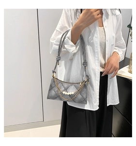 Détail du sac croissant gris avec surpiqûres losanges, chaîne de perles et bandoulière nouée