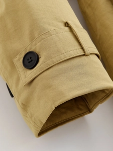 Close-up of khaki cotton jacket sleeve featuring a black four-hole button and fine stitching
