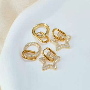 Macro detail of gold stainless steel hoop and star earrings with pavé cubic zirconia