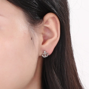 Close-up of anchor earrings in silver finish with crystal stud on female ear