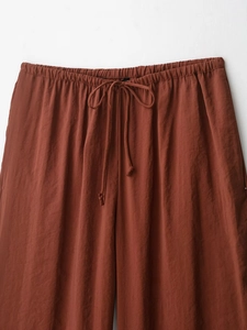 Detail view of elastic waist and drawstring on reddish-brown casual wide-leg trousers