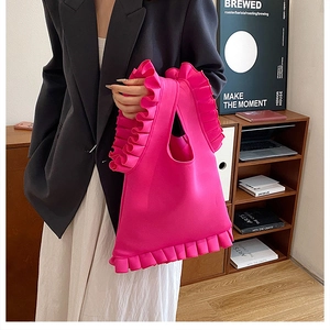 Detail of vibrant pink pleated tote bag with decorative ruffles in a cozy indoor setting